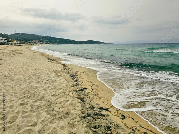 Fototapeta Peaceful beach retreat with gentle waves and soft sandy shore during overcast weather in Sarti on Sithonia peninsula, Greece