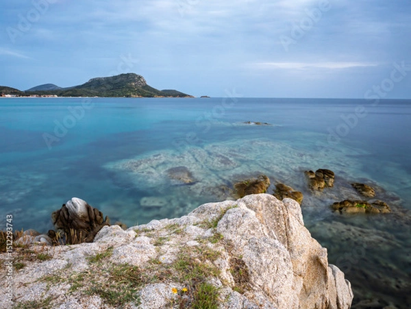 Fototapeta Calm turquoise waters and rocky shoreline at sunset near the coastal hills in Toroni on Sithonia peninsula, Greece
