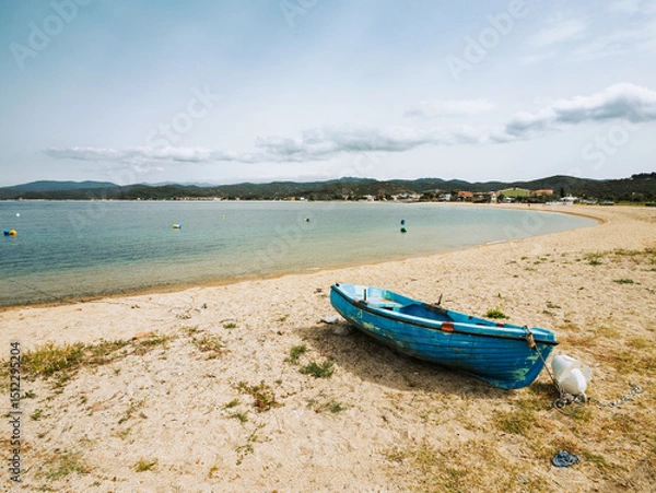 Fototapeta Calm seaside view with a blue boat on the sandy shore of a tranquil beach during the daytime in Toroni on Sithonia peninsula, Greece