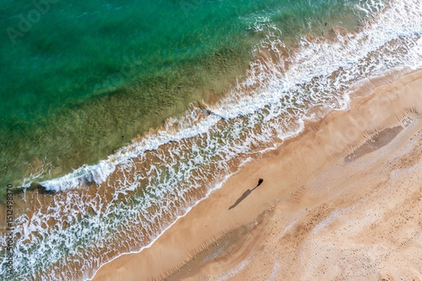 Obraz Aerial drone overhead view of beautiful waves and alone human with big shadow on sand.