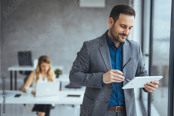 Fototapeta Businessman Using Digital Tablet in Modern Office Setting