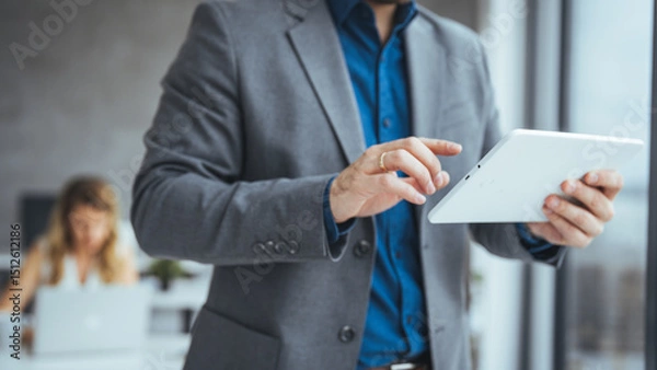 Fototapeta Business Professional Using a Tablet Device in Modern Office Setting