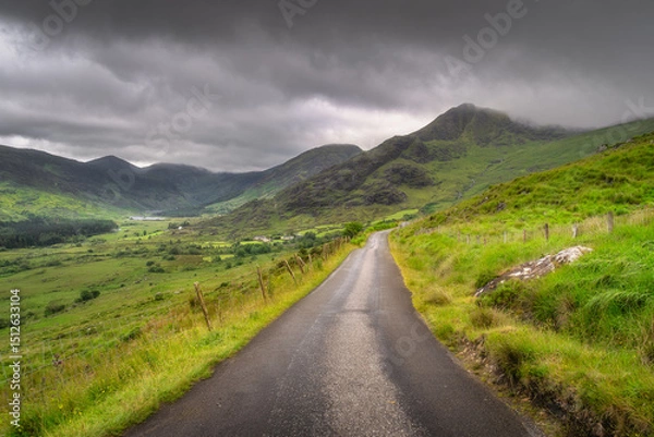 Obraz Explore a serene rural pathway that gracefully winds through vibrant, colorful hills of Black Valley, with majestic clouds encouraging the breathtaking views of the stunning landscape, Kerry, Ireland
