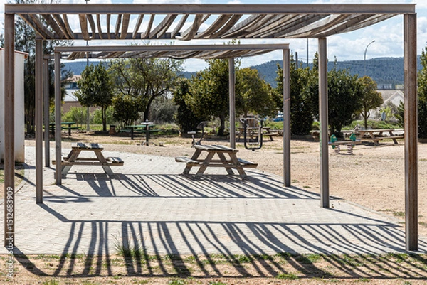 Fototapeta Two Empty gray wooden tables on the green plants background with a pergola