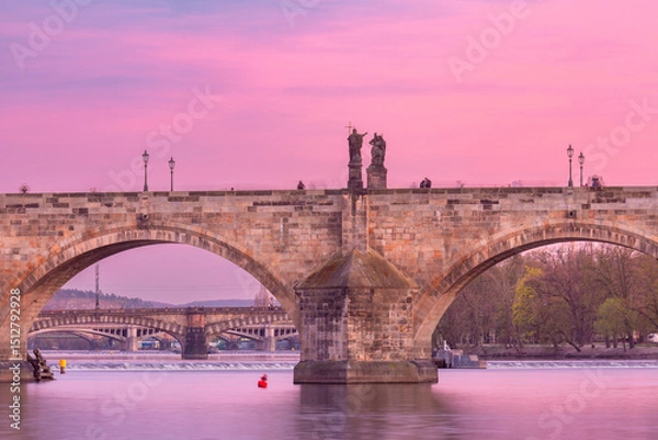 Fototapeta Stone arches and statues of Charles Bridge at sunrise in Prague, Czech Republic
