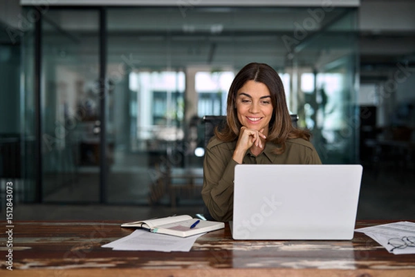 Obraz Smiling professional middle aged female company executive manager working looking at computer at workplace. Happy busy mature business woman entrepreneur in office using laptop at work.