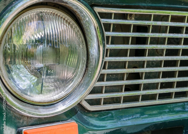 Fototapeta Detail of a rusty green car abandoned by the side of the road