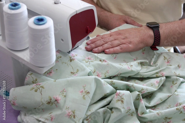 Fototapeta Hands of a tailor working with an overlocker. Overcasting fabric on an overlocker. Concept of sewing baby diapers, bed linen.