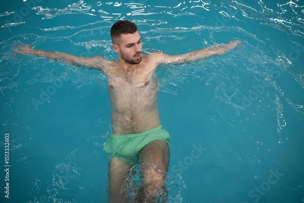 Fototapeta Man floating peacefully in warm spa water with eyes closed and arms outstretched on the edge of the pool.