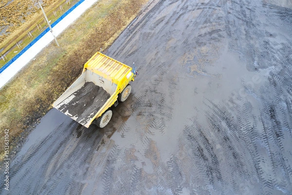 Fototapeta Top view of a yellow dump truck that is working on a dirty site