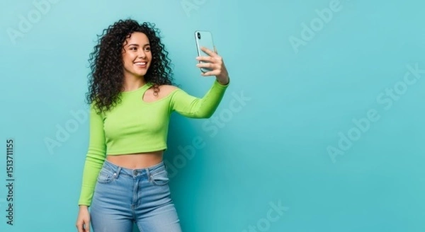 Obraz Cheerful Woman Taking a Selfie with a Smartphone Against a Bright Blue Background