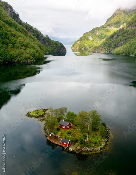 Fototapeta Stunning view of a tranquil island with red cabin surrounded by dramatic Norwegian fjords