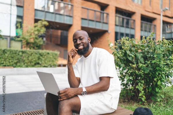 Fototapeta Smiling remote worker embraces creative moment, merging digital tools and positive attitude in a flexible freelance routine outdoors.