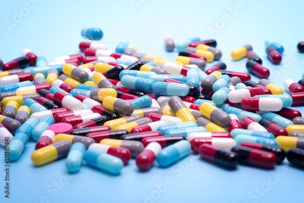 Fototapeta many scattered Colorful pills on blue background.
