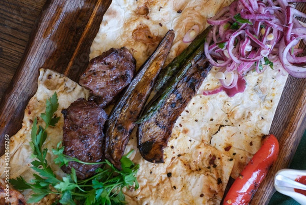 Obraz Grilled meats and vegetables served on flatbread in a rustic setting