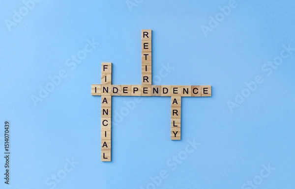 Fototapeta Crossword Financial Independence Retire Early from wooden blocks with letters on blue background. Business FIRE concept. Selective focus and copy space