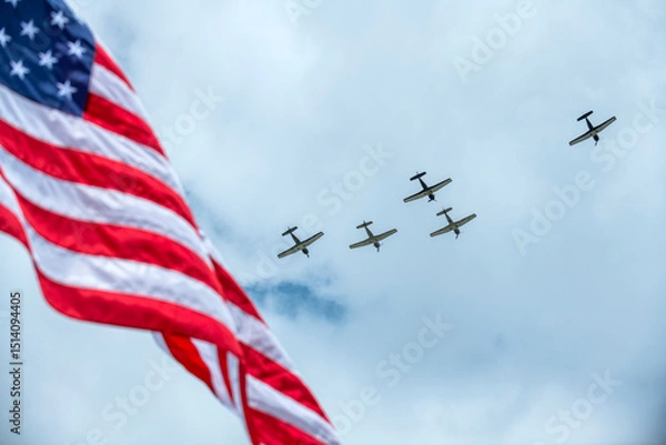 Fototapeta Planes fly over a Memorial Day event with the United States flag in the foreground