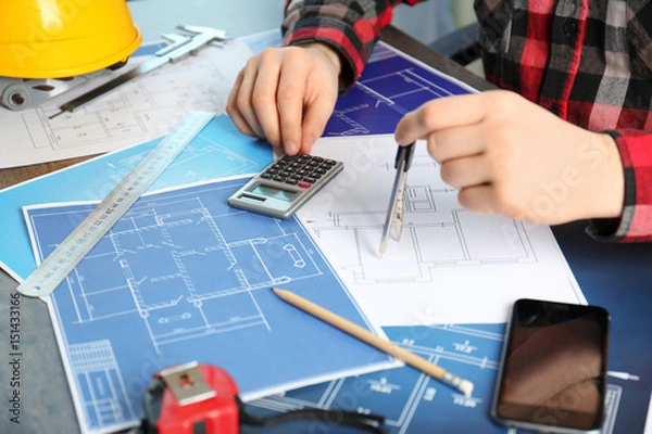Fototapeta Male engineer hands working with blueprints on table