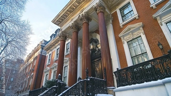Obraz A low angle shot of a brick building with large columns and snow on the railing and trees nearby