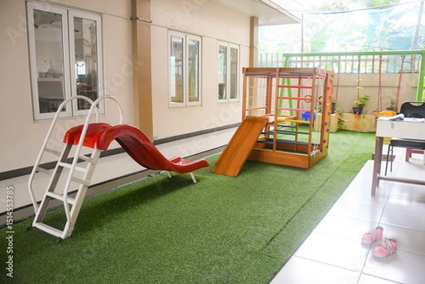 Obraz Set of different cute toys in children's playground. Preschool building exterior with playground and toys on a sunny day