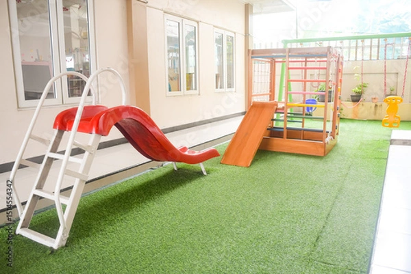 Obraz Set of different cute toys in children's playground. Preschool building exterior with playground and toys on a sunny day