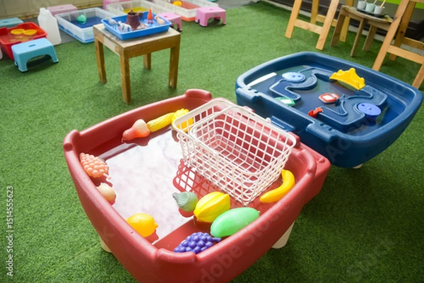 Obraz Set of different cute toys in children's playground. Preschool building exterior with playground and toys on a sunny day