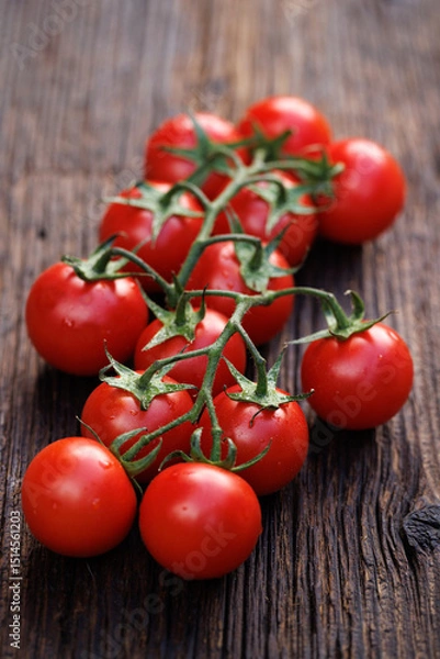 Obraz Fresh Tomatoes on twigs lying on a wooden table, close up view
