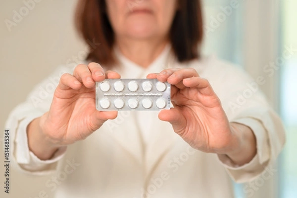 Obraz A woman doctor in a medical coat holds tablets in her open hand. Close-up shows care and expertise in patient treatment. Emphasizes trust, health solutions, and professional responsibility.