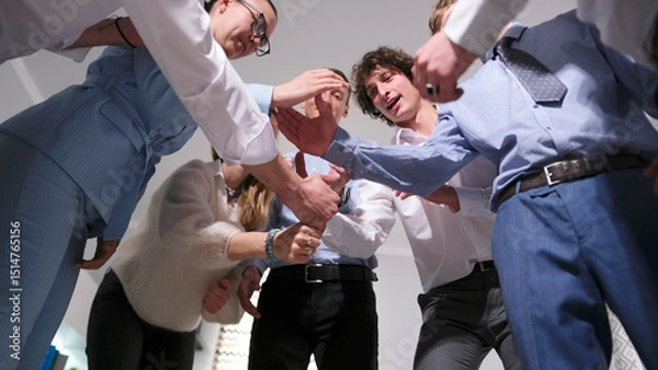 Fototapeta The scene demonstrates camaraderie and teamwork. A group of successful professionals stands in a circle and begins to build a tall tower