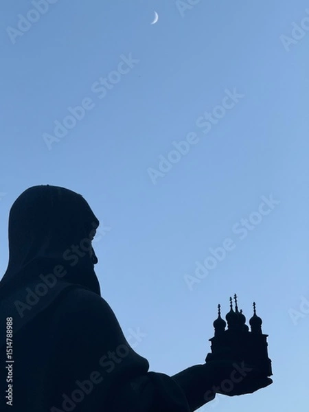 Fototapeta silhouette of a clergyman priest holding a model of a church in his hands against the night sky