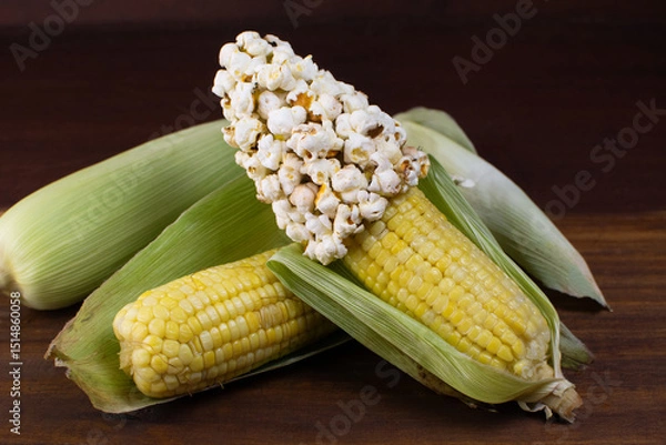 Obraz a couple of corn on a wooden table with corn grains and popcorn