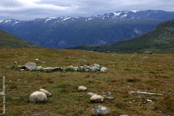 Fototapeta Landscape photo with a view of snowy mountains and large stones in the foreground at sunset on the snowy road Bjørgavegen near Aurlandsfjord in Norway