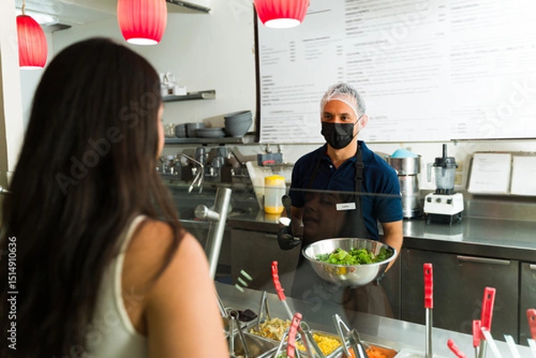 Obraz Restaurant worker serving customer fresh salad at salad bar