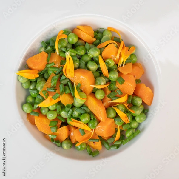 Obraz Fresh garden peas and carrots are cooked with salted butter, then garnished with chives and bright marigold flowers for an appealing and colorful side dish.