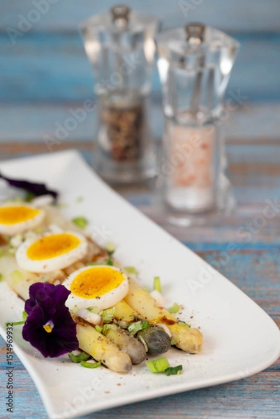 Obraz Baked asparagus with boiled egg in big white plate on blue background. High quality photo