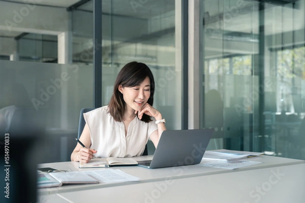 Fototapeta Asian mature woman using laptop computer for business studying, watching online virtual webinar training, videoconference. Focused saleswoman businesswoman working in office, writing notes. Copy space