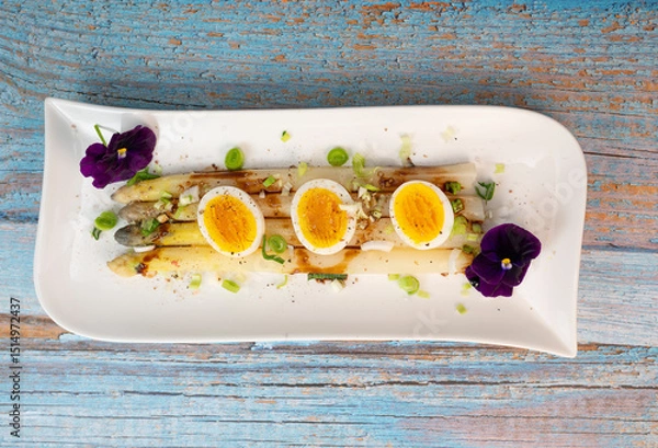 Obraz Baked asparagus with boiled egg in big white plate on blue background. High quality photo
