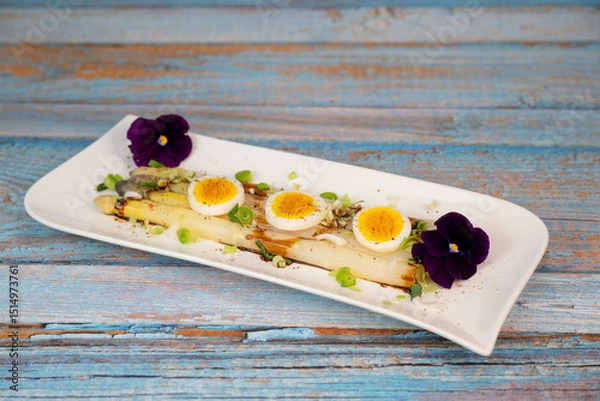 Obraz Baked asparagus with boiled egg in big white plate on blue background. High quality photo