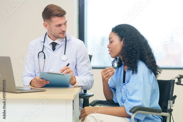 Obraz doctor in white gown with stethoscope,asking a woman patient on wheelchair a present illness and writing paper on clipboard to diagnosis and treatment