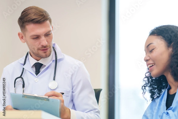 Obraz doctor in white gown with stethoscope,asking a woman patient on wheelchair a present illness and writing paper on clipboard to diagnosis and treatment