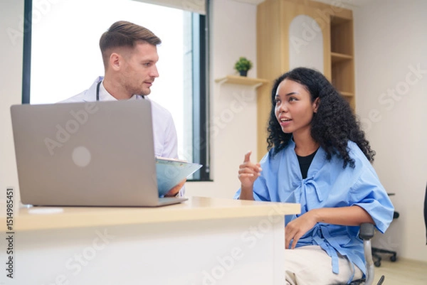 Obraz doctor in white gown with stethoscope,asking a woman patient on wheelchair a present illness and writing paper on clipboard to diagnosis and treatment