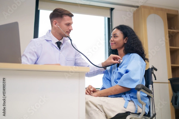 Obraz caucasian doctor in white gown using stethoscope to listen heart beat an afro hair woman client in examine room at hospital
