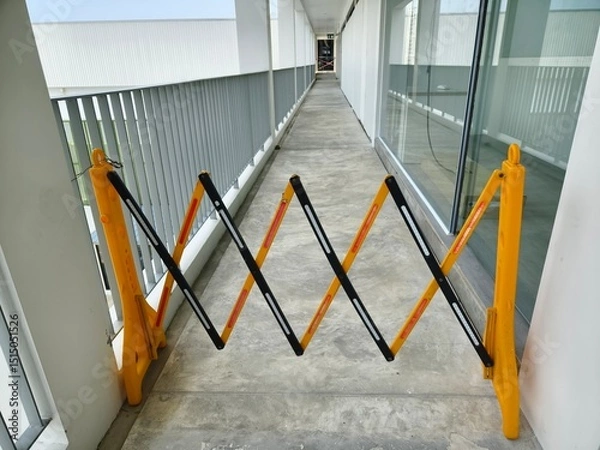 Fototapeta A bright yellow and dark black barrier is in the center of a hallway