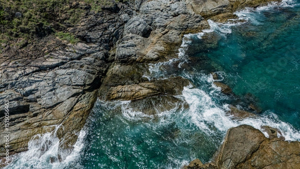 Fototapeta Rocky shoreline where the waves are dramatically crashing against the rocks and stones