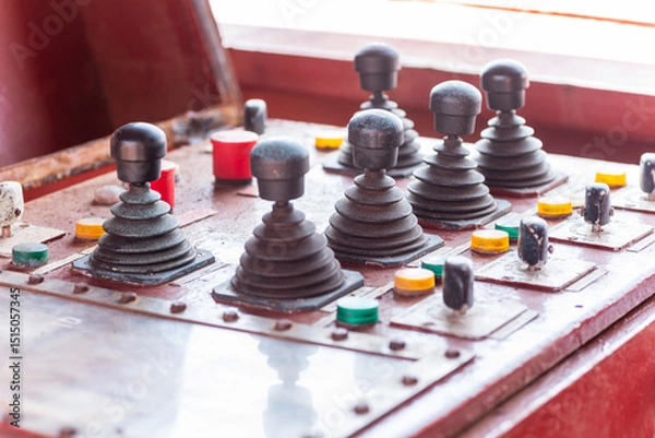Fototapeta Control console with switches and joysticks used to operate the mooring winches on a commercial cargo ship.