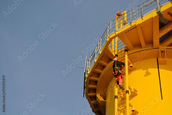 Fototapeta GWO-Certified Offshore Technician Rigger Climbing Wind Turbine Foundation Ladder Wearing Safety PPE.