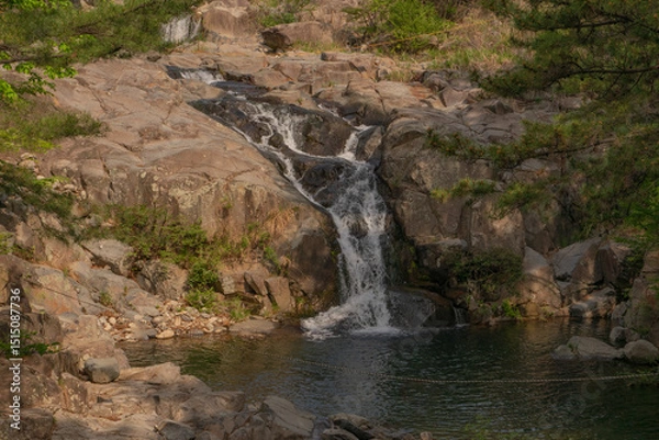 Fototapeta Jangsan Waterfall tranquil flow surrounded by lush forest, Busan, South Korea, nature landscape