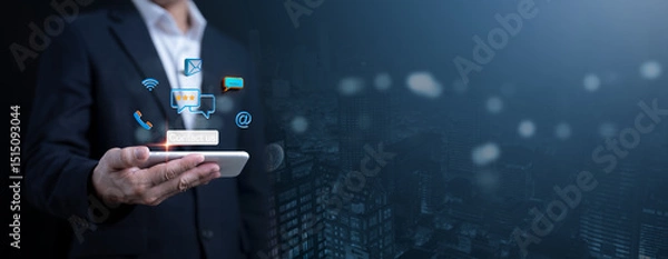 Fototapeta Digital connectivity and communication concept with a businessman holding a smartphone, surrounded by glowing icons for messaging, email, call, and social media.