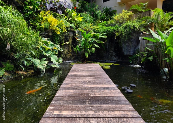 Fototapeta A charming wooden bridge spans a tranquil pond in a serene garden