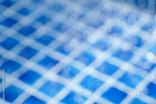Fototapeta Abstract blue bokeh background of sunlight hitting water drops falling in a pool with blue tiled floor. Concept of nature background.
